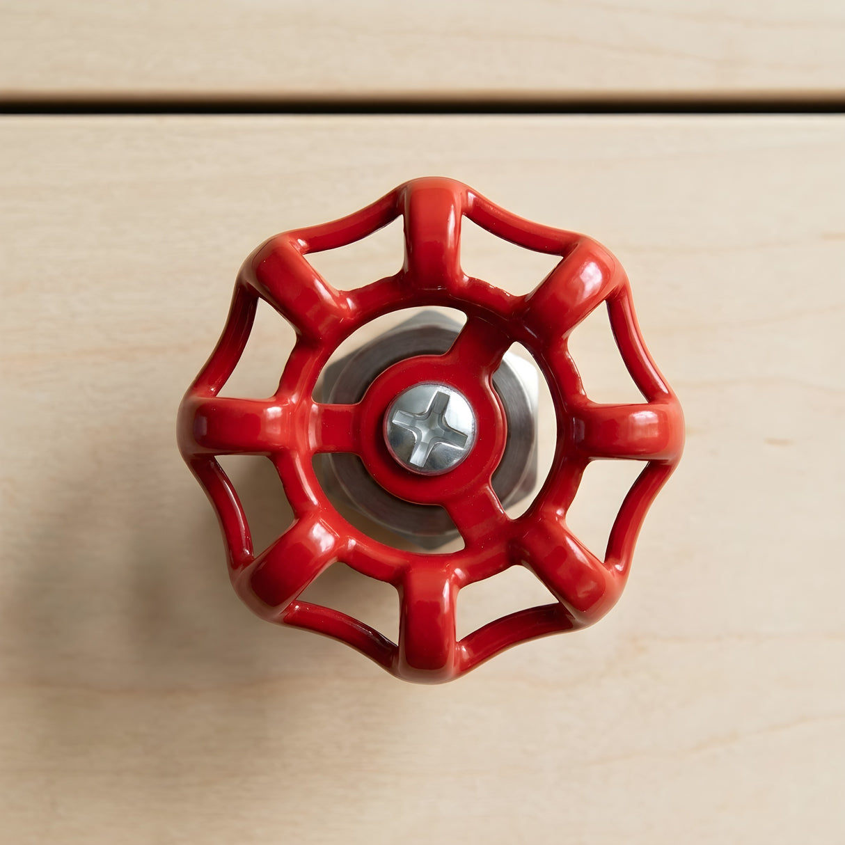 Bouton de meuble volant rouge en inox sur meuble en bois