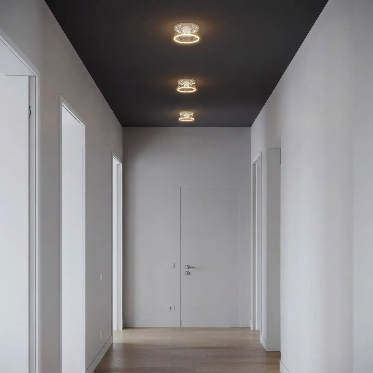 Tre E27 LED-donutpærer i klart glas på række i loftet i en enkel gang