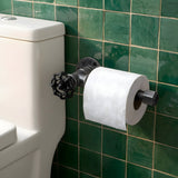 Toiletrulleholder i sort støbejern med håndhjul på en væg med grønne zellige-fliser ved siden af toilettet